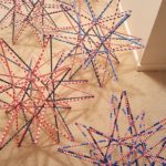 series of straw stars pictured on the floor, all with patriotic red/white/blue color themes