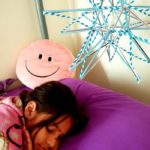 Young girl sleeping on a bed underneath one of April's straw stars hanging from the ceiling