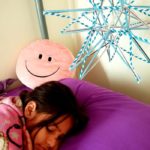 Young girl sleeping on a bed underneath one of April's straw stars hanging from the ceiling